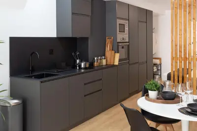 a kitchen with gray cabinets and a white table at Valencia Leones by Concept Flats in Valencia
