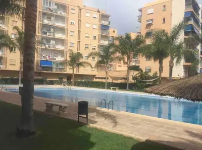 a swimming pool with a bench and some buildings at Beach apartment in Valencia