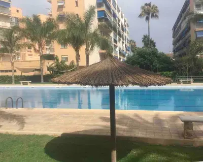 a straw umbrella in front of a swimming pool at Beach apartment in Valencia