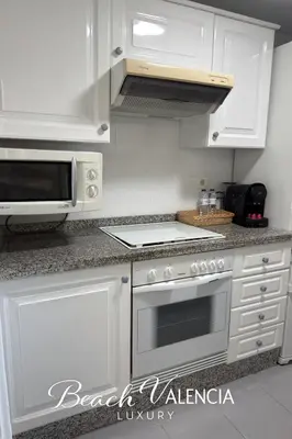 a kitchen with white cabinets and a stove top oven at BEACH VALENCIA LUXURY D7-21 Apartment with terrace and sea views with two rooms in Valencia