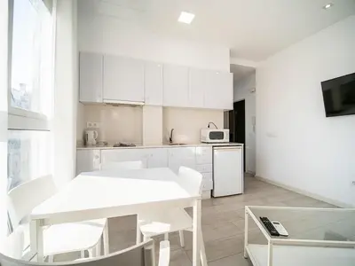 a kitchen with white cabinets and a white table and chairs at Apartment Ruzafa Market 9C in Valencia