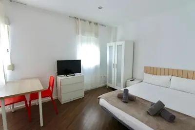 a small white room with a bed and a television at Tu Estudio En El Centro-Ruzafa 10A in Valencia