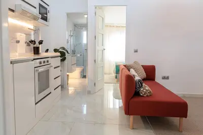 a living room with a red chair and a kitchen at Top Floor 2 Bedroom Apartment with Terrace in Valencia