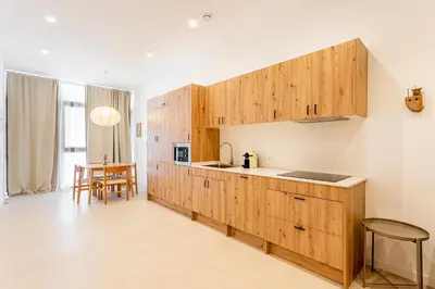 a kitchen with wooden cabinets and a table at B - Design apartment at El Grao close to the beach in Valencia