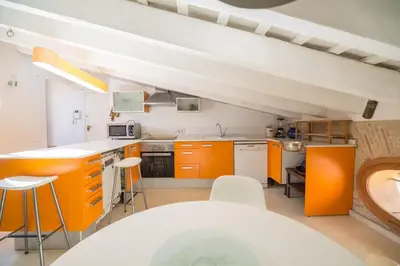 a kitchen with orange cabinets and a white counter top at Ático Exclusivo del Siglo XVI con Dos Terrazas en el Corazón de Ciutat Vella in Valencia