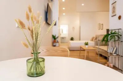 a vase with flowers sitting on a table in a living room at Hridaya El Grao close to the sea in Valencia