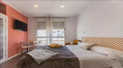 a bedroom with a large bed and a desk and a window at Tu Estudio En El Centro-Ruzafa 10C in Valencia