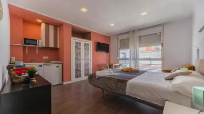 a bedroom with orange walls and a bed and a kitchen at Tu Estudio En El Centro-Ruzafa 10C in Valencia