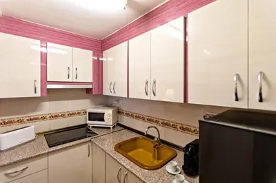 a kitchen with white cabinets and a sink and a microwave at A pié de playa Rincón acogedor Amanecer in Cullera