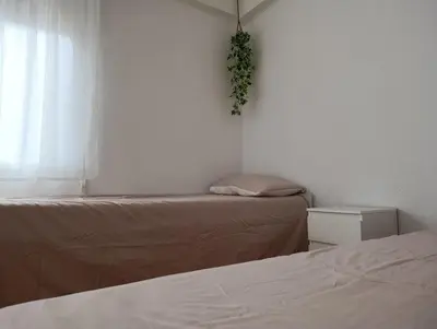 a bedroom with two beds and a window with a plant at El otro cielo Playamonte in Navarrés