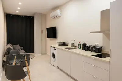a kitchen with a sink and a table with chairs at Roca Collection MSuites in Valencia