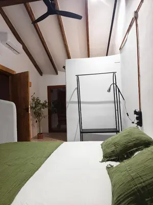a bedroom with a bed and a black chair at Casa Abadía Alojamiento completo boutique cerca de Valencia in Alfarp