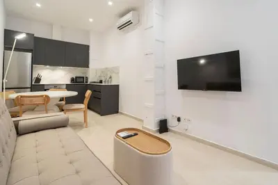 a living room with a couch and a tv on a wall at VLC Host - Cubells 8 in Valencia