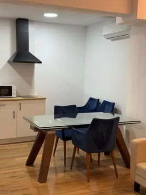a dining room with a glass table and blue chairs at Apartamento junto a la playa in Valencia