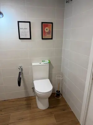 a bathroom with a toilet with two pictures on the wall at Apartamento junto a la playa in Valencia