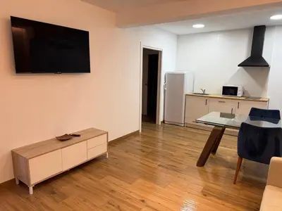 a living room with a table and a tv on the wall at Apartamento junto a la playa in Valencia