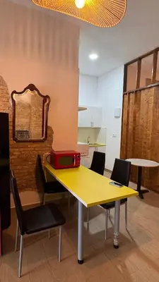 a yellow table with chairs and a red suitcase on it at Gran Loft en planta baja en el Centro de Valencia in Valencia