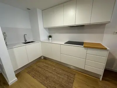 a kitchen with white cabinets and a sink and a rug at 60m2 Cozy Apartament in Valencia