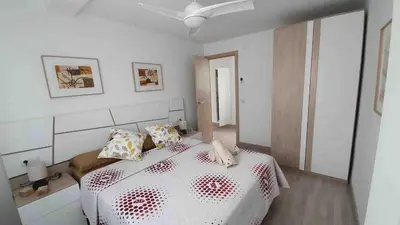 a white bedroom with a bed and a ceiling fan at Apartment near the beach and the City of Sciences in Valencia