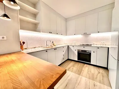 a large kitchen with white cabinets and a wooden table at Joaquin Costa Urban Flat in Valencia