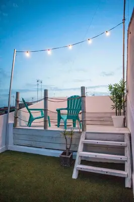 two green chairs and a table on a deck with lights at Apartment next to the beach in Valencia