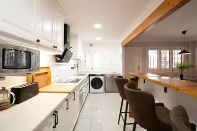 a kitchen with white cabinets and a counter with chairs at Casa Boutique Playa y Valencia in El Puig