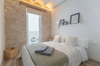 a bedroom with a large bed with a brick wall at Borrull Historic Center Premiere in Valencia