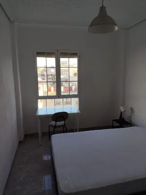 a bedroom with a bed and a table and a window at Carmen & Alejandro Home in Valencia
