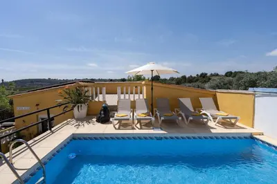 a swimming pool with chairs and an umbrella on a balcony at Casa Rosa Longterm Living and Workspace in Monserrat