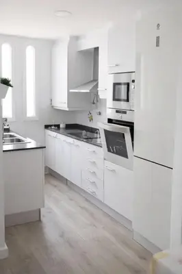 a white kitchen with white cabinets and appliances at Terraced House MARIELISA in Puebla de Farnals