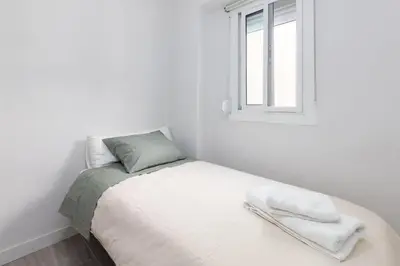 a white bedroom with a bed with a window at Mislata Apartment in Valencia
