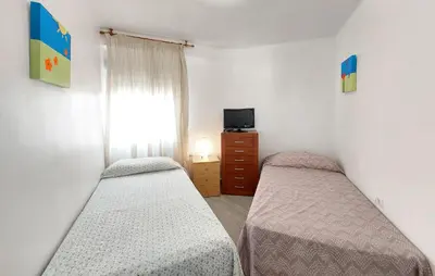 two beds in a room with a tv and a window at Lovely Apartment In Tavernes De La Valldig in Tavernes de Valldigna