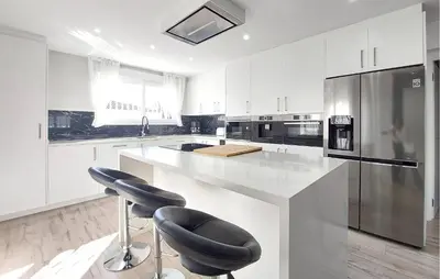 a kitchen with white cabinets and a large island with black stools at Awesome Home In Olocau in Olocau