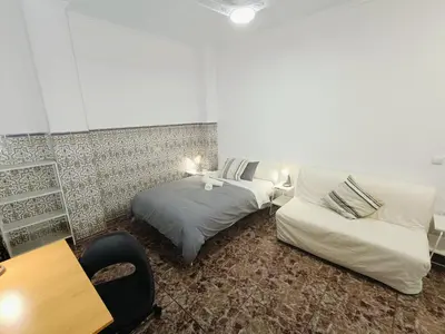 a hotel room with two beds and a chair at Espectacular estudio en PB con terraza privada in Valencia