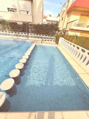 a swimming pool with stools in front of a building at Puerto Beach House in Puebla de Farnals