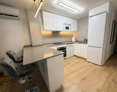 a kitchen with white cabinets and a desk and a chair at Ático Premium Centro de Tavernes, Terraza & BBQ in Tavernes de Valldigna