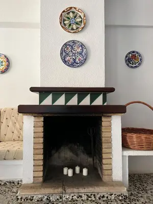 a living room with a fireplace with plates on the wall at Casa Enredadera in Mareny Blau