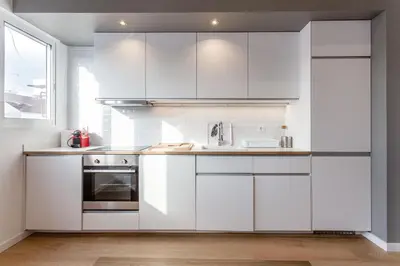 a white kitchen with white cabinets and a window at Apartment Ruzafa Puerto Rico in Valencia