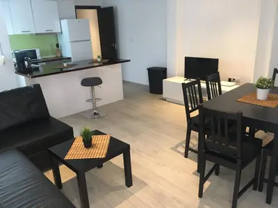 a living room with a table and chairs and a kitchen at Bienvenido a Lovely Apartment, Cullera in Cullera
