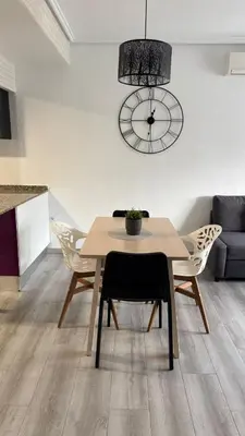a dining room with a table and chairs and a clock at Apartamento con piscina, playa y cerca de Valencia in Puebla de Farnals