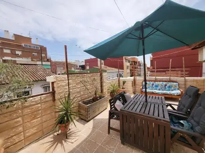a patio with a bench and an umbrella on a balcony at Piso con terraza en Cabanyal in Valencia