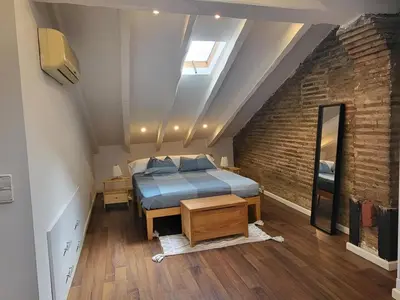 a attic bedroom with a bed and a brick wall at Precioso apartamento en casa histórica en la playa in Valencia