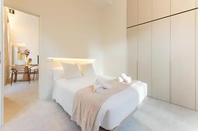 a white bedroom with a white bed with towels on it at GMG Apartments & Suites in Valencia