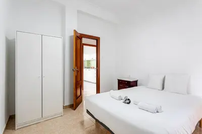 a white bedroom with a large bed and a mirror at Guest Ready - Bright flat well‑located urban stay in Valencia