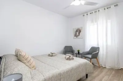 a white bedroom with a bed and two chairs at Estrella Maya Escapada Tranquila con encanto único in Torrent