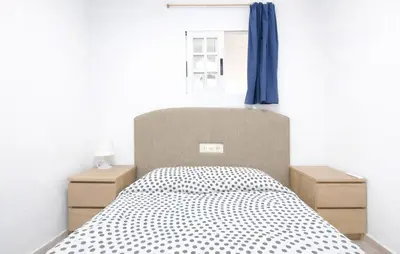 a bedroom with a bed and a blue curtain at 4 Bedroom Stunning Home In Sueca in Sueca