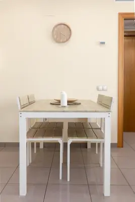 a white table with chairs and a clock on the wall at Patacona Azud in Valencia