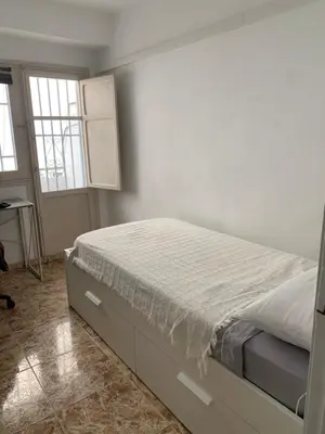 a bedroom with a bed and a desk and two windows at Habitacion individual cerca del puerto in Valencia