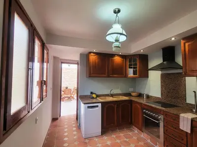 a kitchen with wooden cabinets and a white dishwasher at Casa ALFANG in Torrent