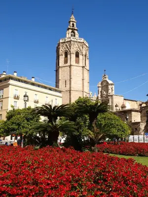 a building with a clock tower and a field of red flowers at SingularStays Botanico 29 Rooms in Valencia
